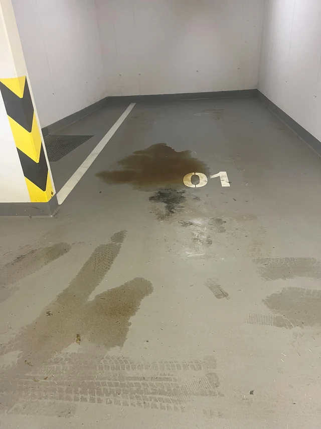 Garážové stání 01 před čištěním, s viditelnými nánosy a stopami provozu na podlaze.