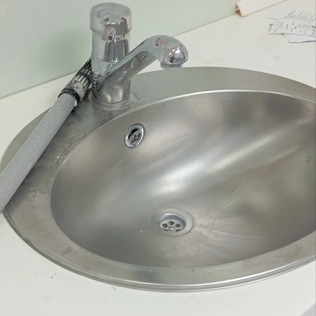 A stainless steel sink with visible deposits around the rim and inside the basin before cleaning.